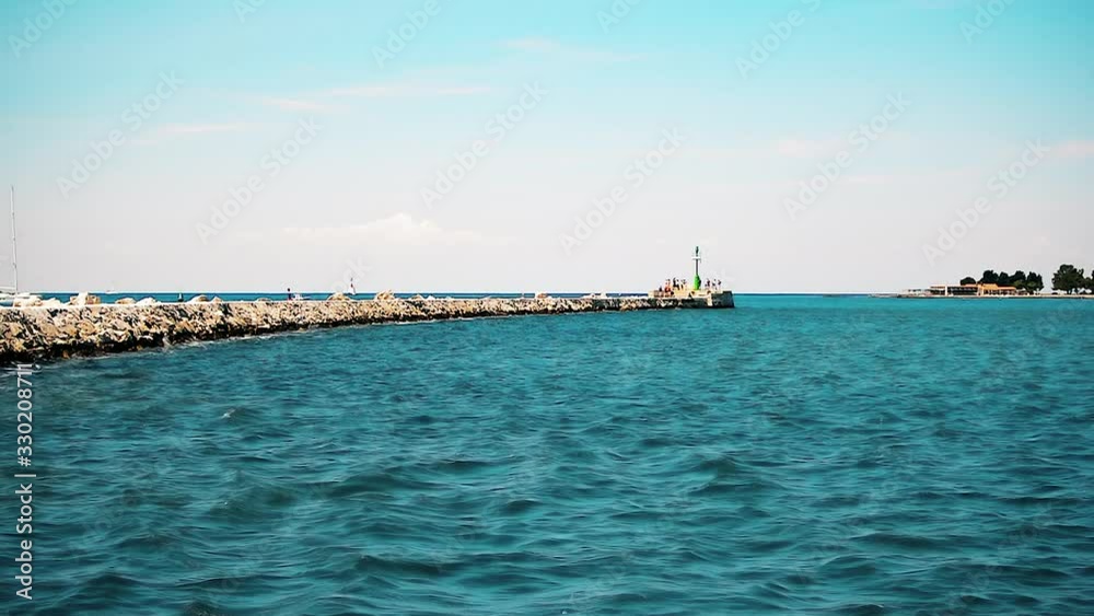 View to the big breakwater surrounded by sea and with signal light at the end in Umag, Croatia. View to the big breakwater surrounded by sea and with signal light at the end in Umag, Croatia.