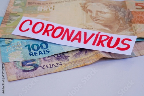 Brazilian Real banknotes and Chinese Yuan banknotes with Coronavirus inscription. Coronavirus alert. 