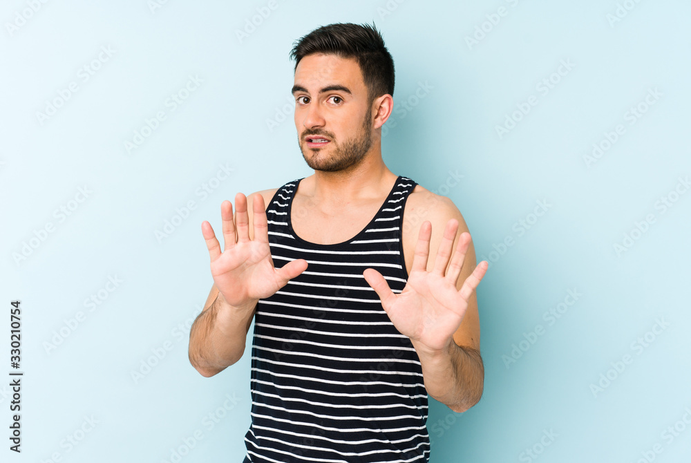 Young caucasian man isolated on blue background rejecting someone showing a gesture of disgust. Young caucasian man isolated on blue background rejecting someone showing a gesture of disgust.