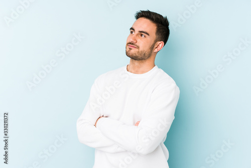 Young caucasian man isolated on blue background dreaming of achieving goals and purposes