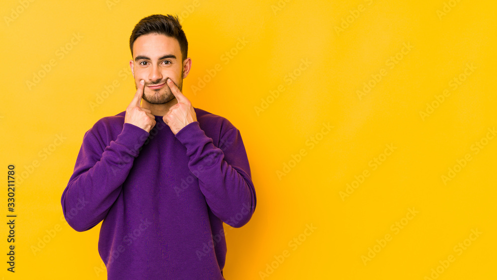 Young caucasian man isolated on yellow bakground doubting between two options. Young caucasian man isolated on yellow bakground doubting between two options.
