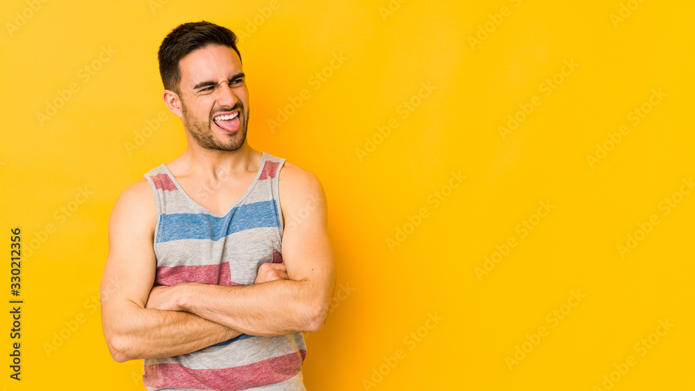 Young caucasian man isolated on yellow bakground funny and friendly sticking out tongue. Young caucasian man isolated on yellow bakground funny and friendly sticking out tongue.