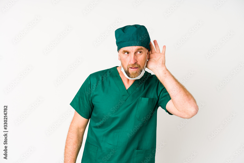 Surgeon senior man isolated on white background trying to listening a gossip. Surgeon senior man isolated on white background trying to listening a gossip.