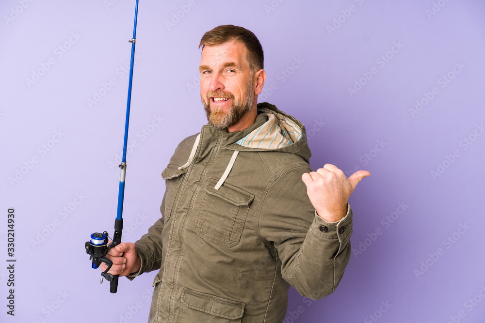 Senior fisherman isolated on purple background points with thumb finger away, laughing and carefree. Senior fisherman isolated on purple background points with thumb finger away, laughing and carefree.