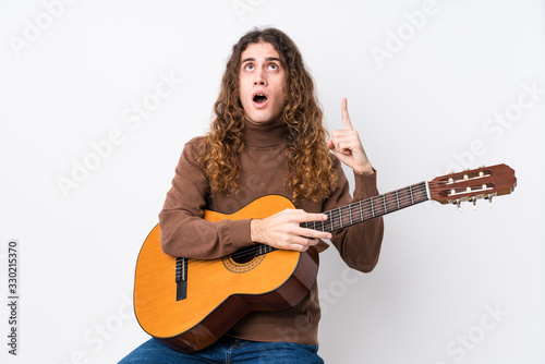 Young caucasian man playing guitar isolated pointing upside with opened mouth.