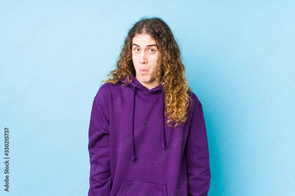 Long hair man posing isolated shrugs shoulders and open eyes confused. Long hair man posing isolated shrugs shoulders and open eyes confused.