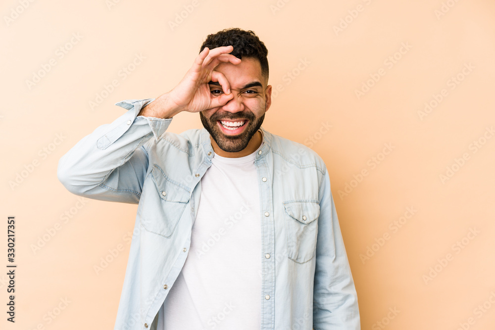 Young mixed race arabic man isolated excited keeping ok gesture on eye. Young mixed race arabic man isolated excited keeping ok gesture on eye.
