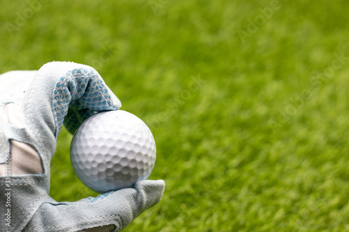 Golfer is holding golf ball on green grass background