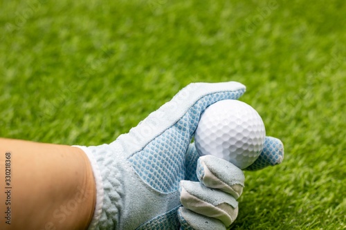 Golfer is holding golf ball on green background