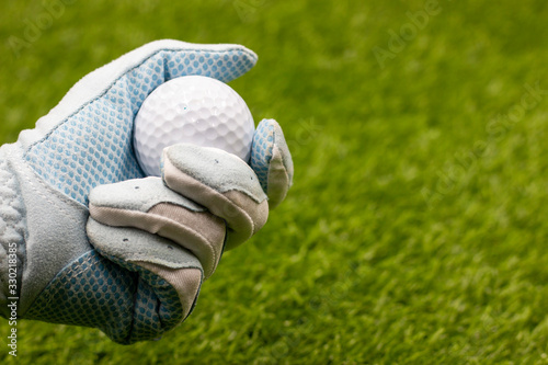 Golfer is holding golf ball on green background