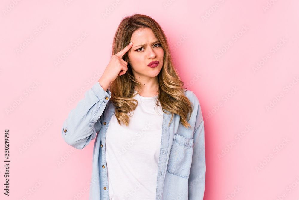 Young caucasian woman isolated on pink background pointing temple with finger, thinking, focused on a task. Young caucasian woman isolated on pink background pointing temple with finger, thinking, focused on a task.