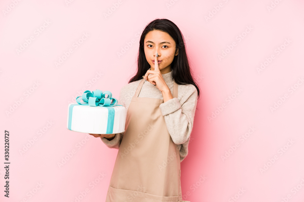 Young chinese woman holding a cake isolated showing number two with fingers. Young chinese woman holding a cake isolated showing number two with fingers.