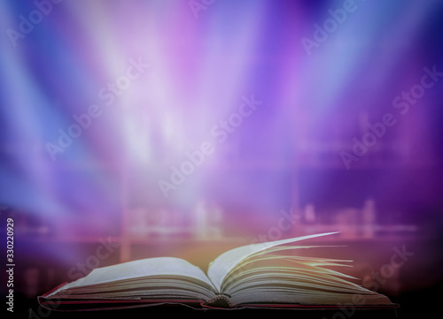 The blurred book that is bewitched with magic, the magic light in the dark, with the bright light shining down as the power to search for knowledge. For research and use as a blurred background © Ping198