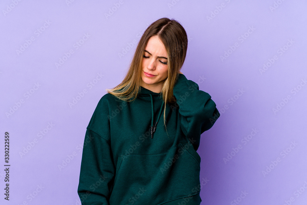 Young caucasian woman isolated on purple background having a neck pain due to stress, massaging and touching it with hand.