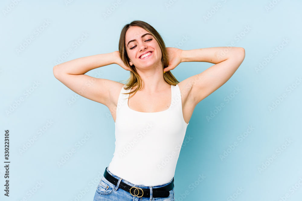 Young caucasian woman isolated on blue background stretching arms, relaxed position.