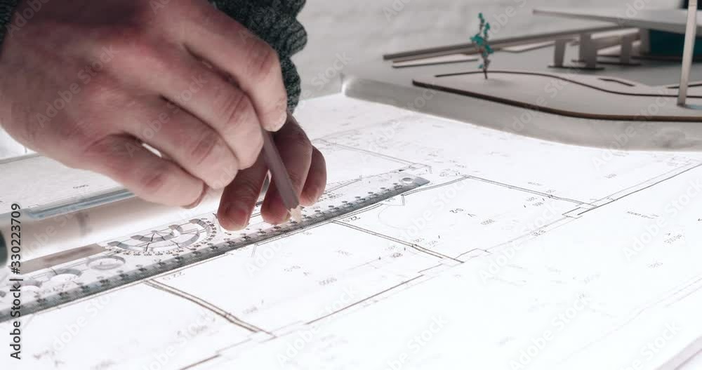 Close up of Man’s hands drawing lines on the Large Format Paper at Modern Office. Architect using Ruler and Pencil to make Blueprints on the Paper. Having very Responsible Job. Great work.
