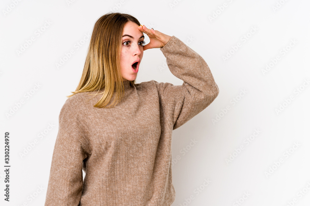 Young caucasian woman isolated on white background looking far away keeping hand on forehead.