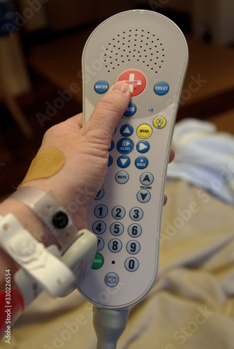Hand of a caucasian patient pressing the call for nurse button