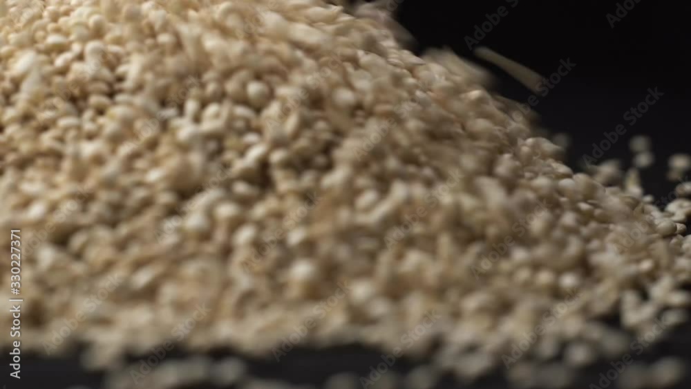 Quinoa poured on black rotating table in kitchen with black background. Chef prepares healthy food with quinoa. The most popular dish with this seed is poke. Quinoa poured on black rotating table in kitchen with black background. Chef prepares healthy food with quinoa. The most popular dish with this seed is poke.