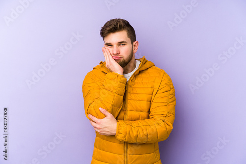 Young man isolated on purple background who is bored, fatigued and need a relax day.