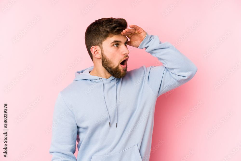 Young caucasian man isolated on pink background looking far away keeping hand on forehead. Young caucasian man isolated on pink background looking far away keeping hand on forehead.