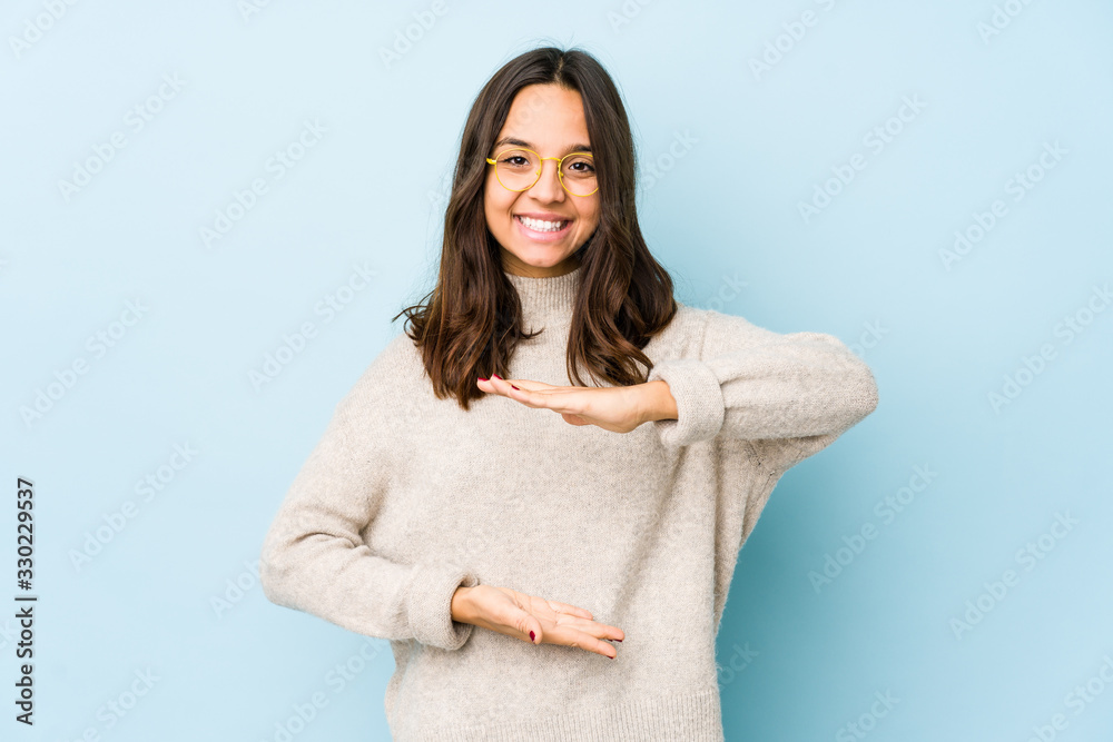 Young mixed race hispanic woman isolated holding something with both hands, product presentation. Young mixed race hispanic woman isolated holding something with both hands, product presentation.