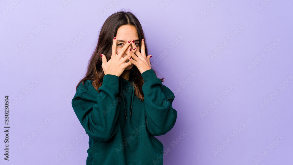 Young mixed race hispanic woman isolated blink at the camera through fingers, embarrassed covering face. Young mixed race hispanic woman isolated blink at the camera through fingers, embarrassed covering face.