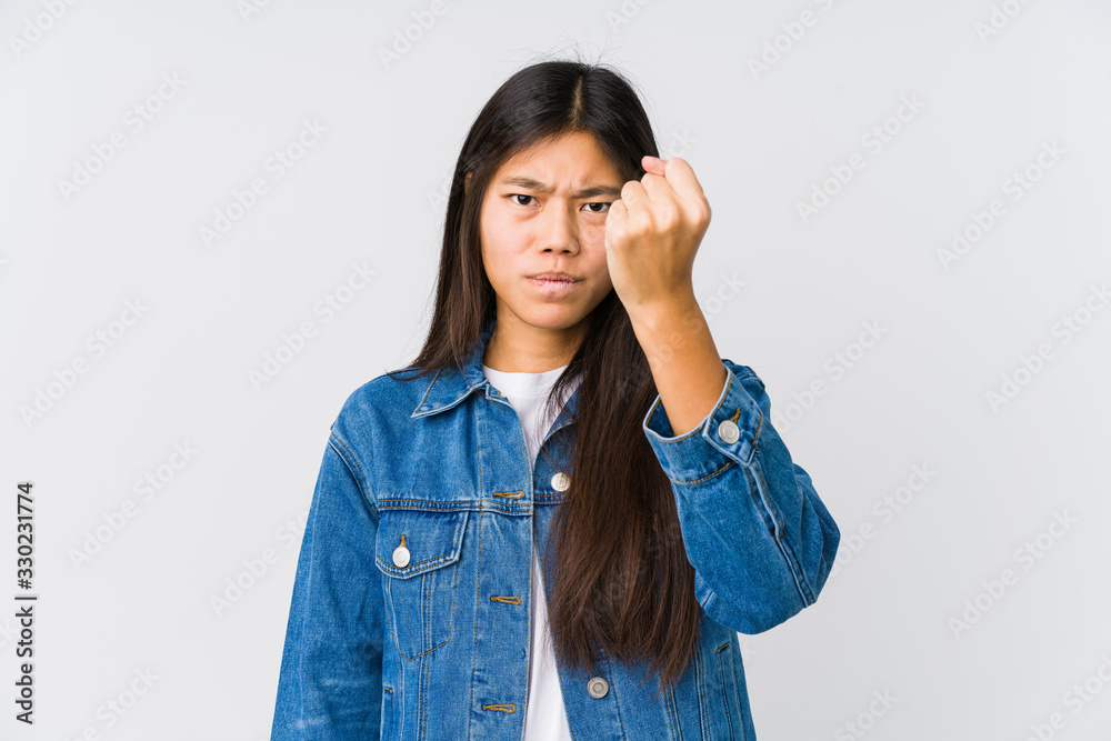Young asian woman showing fist to camera, aggressive facial expression. Young asian woman showing fist to camera, aggressive facial expression.