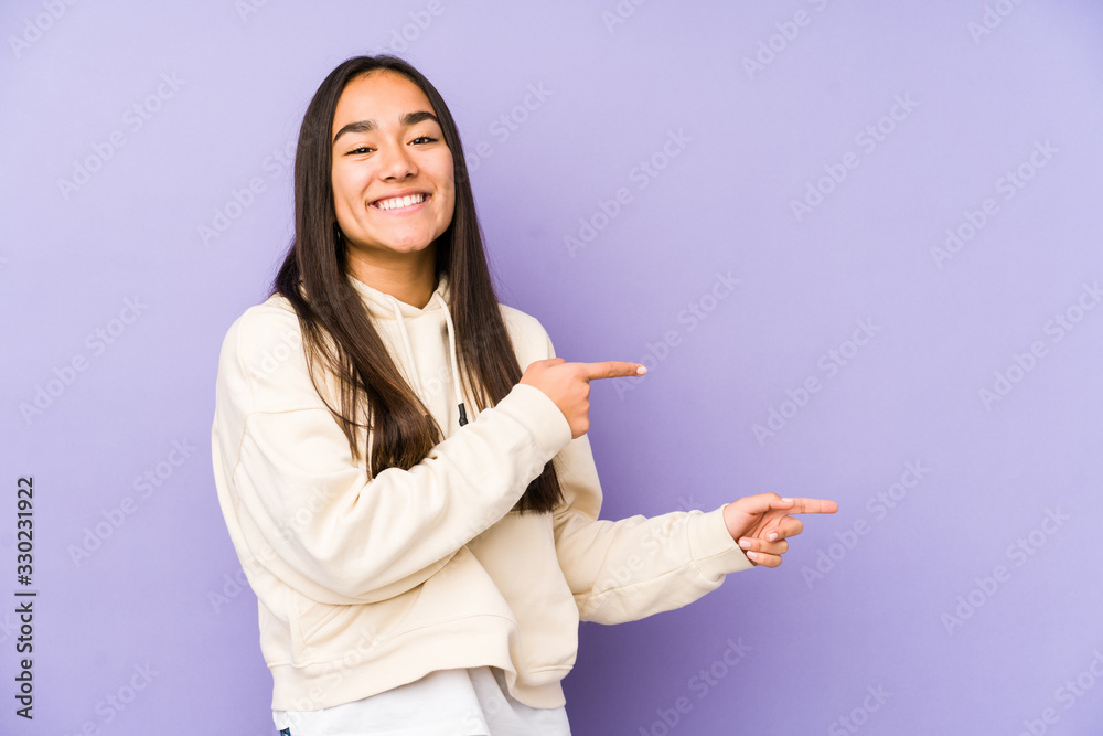 Young woman isolated on a purple background excited pointing with forefingers away. Young woman isolated on a purple background excited pointing with forefingers away.