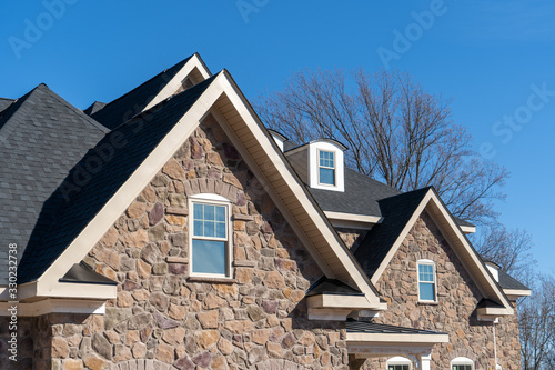 фотографія Pointed  gable roofs with attic windows on a house covered with manufactured ven