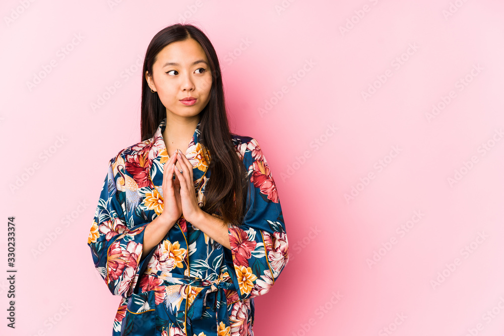 Young chinese woman wearing a kimono pajama isolated making up plan in mind, setting up an idea.