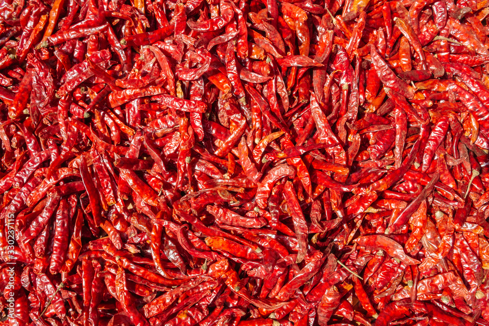 Fototapeta premium Texture background and pattern of cultivated dried red hot chili peppers with Capsaicin. Top view local organic product, outdoor natural sun drying method.