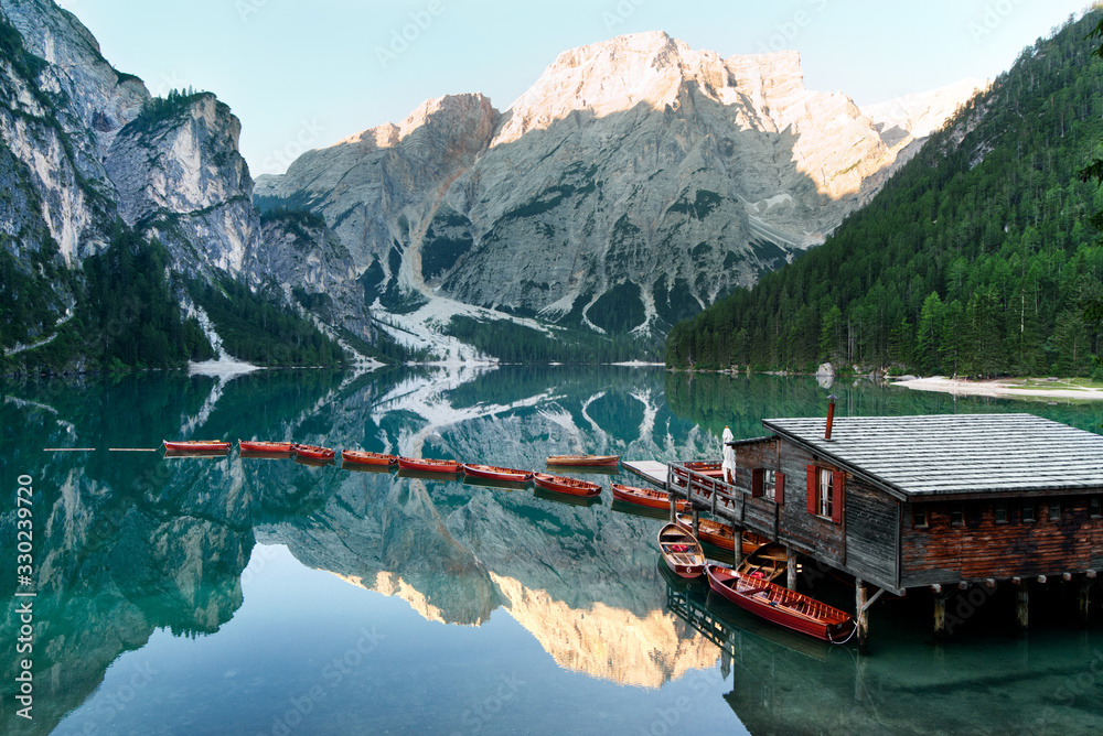 A scenic lake surrounded by the valleys; wooden rowboats berthed by the dock - obrazy, fototapety, plakaty 
