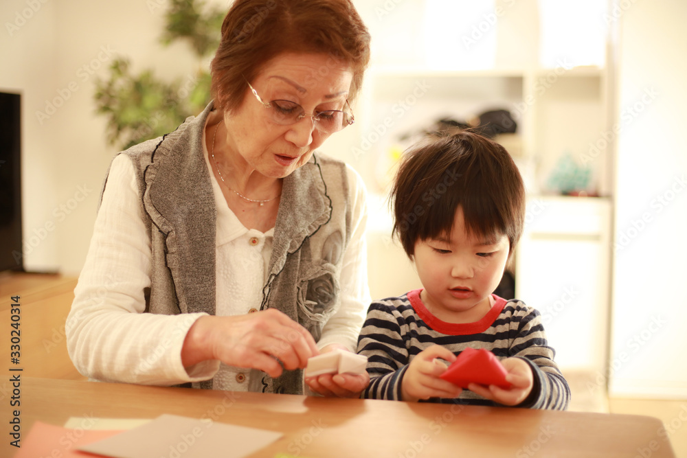 折り紙で遊ぶシニア女性と男の子 折り紙で遊ぶシニア女性と男の子