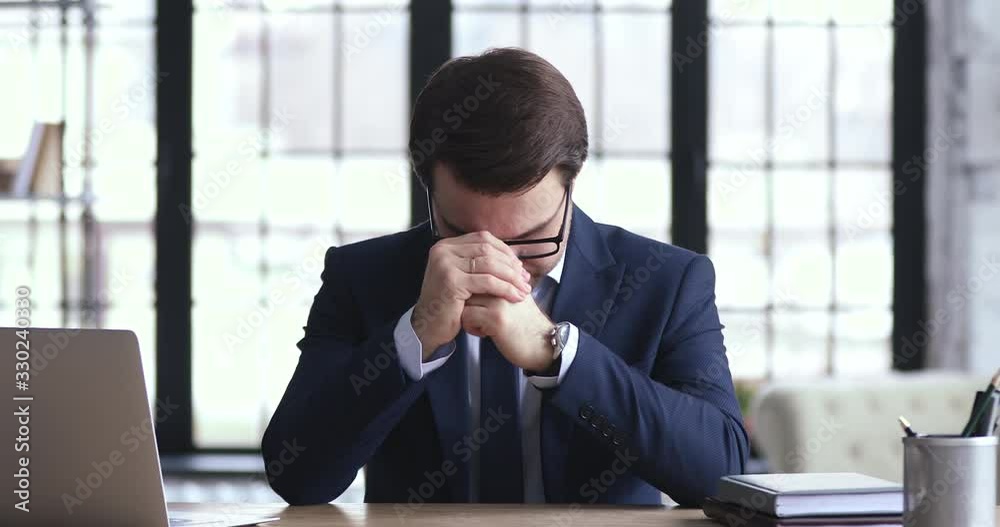 Depressed businessman ceo feels desperate loser frustrated by business failure sitting at office desk. Stressed insolvent executive in nervous tension worries about company bankruptcy problem concept.