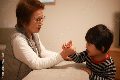 腕相撲する男の子とシニア女性