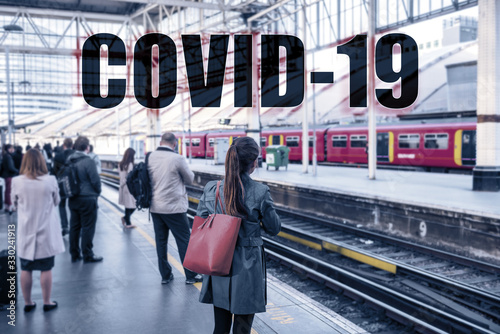 COVID-19 Text sign over travellers commuting at train station. Travel ban quarantine for public transport over Corona virus fear. Coronavirus panic social distancing people.