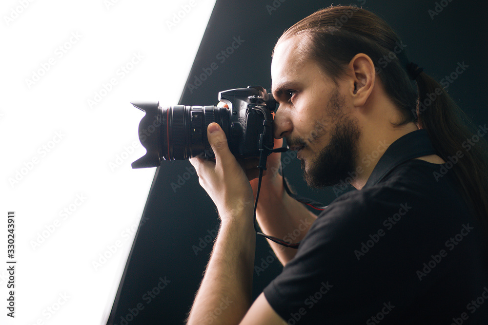 A photographer in a black T-shirt is holding a camera. The guy in the dark. Silhouette A photographer in a black T-shirt is holding a camera. The guy in the dark. Silhouette