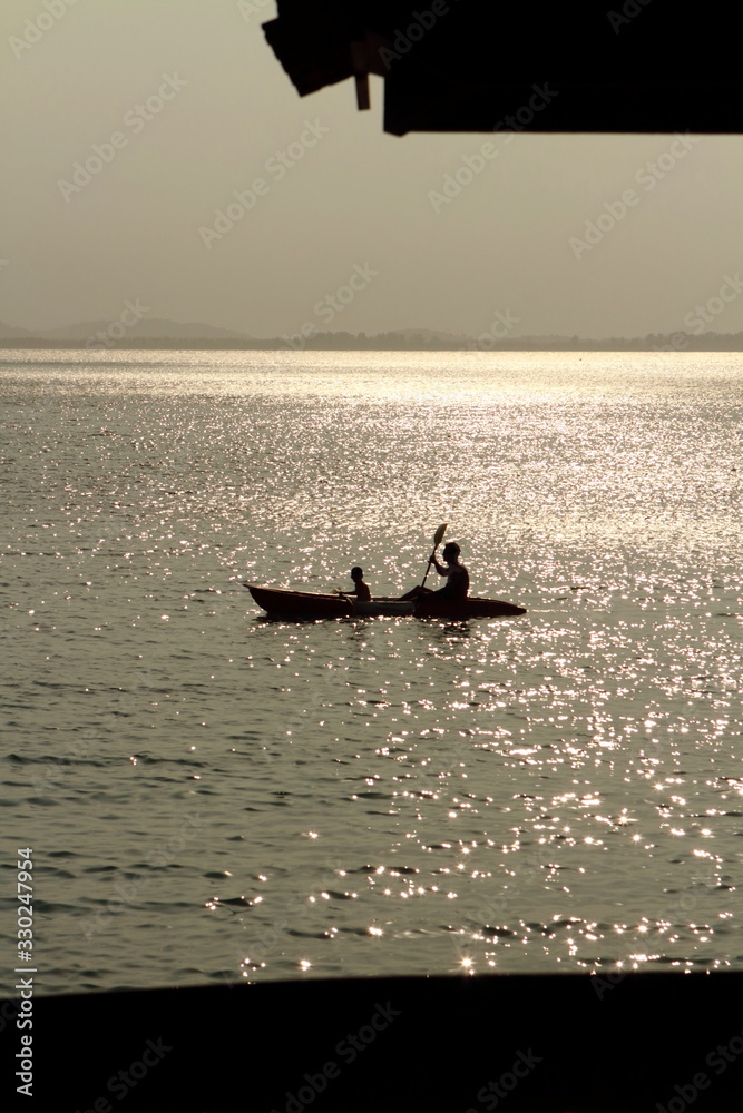 Father and son kayaking at sea sunset time. time of family and relax. Silhouette.