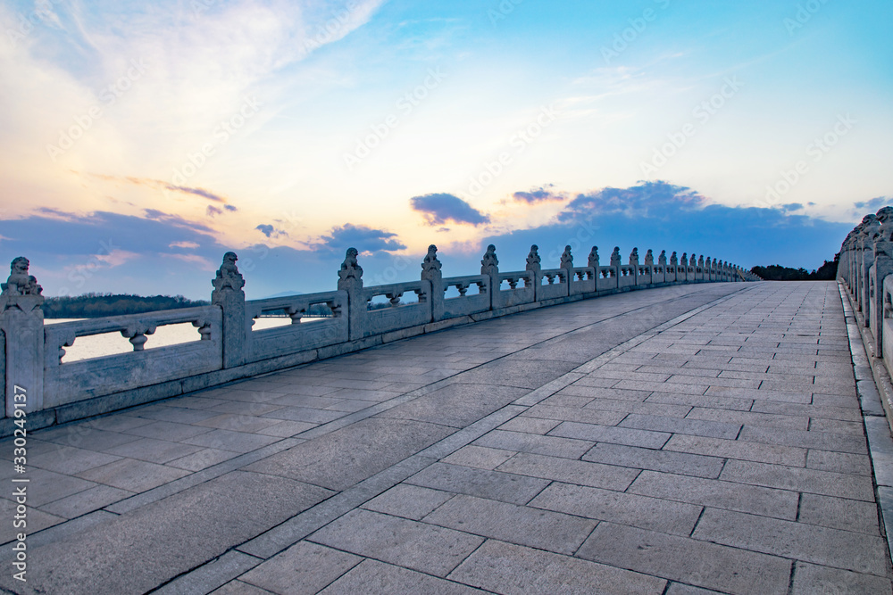 Fototapeta premium Sunset over the Seventeen Hole Bridge in the Summer Palace in Beijing, China