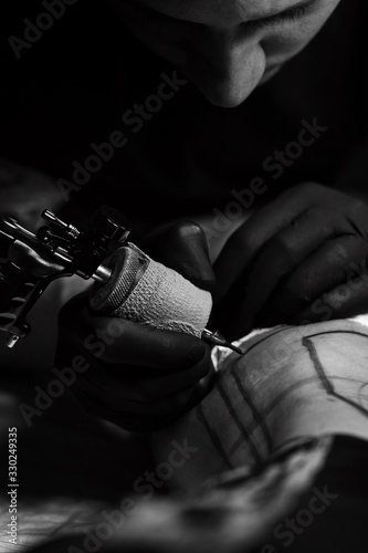 Process of making tattoo close-up. Professional tattoo artist makes tattoo on young man leg. Process of making tattoo in studio.
