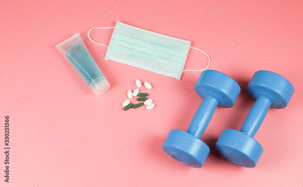 Hand Sanitizer , Disposable Hygienic Mask,medical pill or vitamin and dumbell on pink background with copy space . protection against pm2.5 and COVID-19 concept. Hand Sanitizer , Disposable Hygienic Mask,medical pill or vitamin and dumbell on pink background with copy space . protection against pm2.5 and COVID-19 concept.