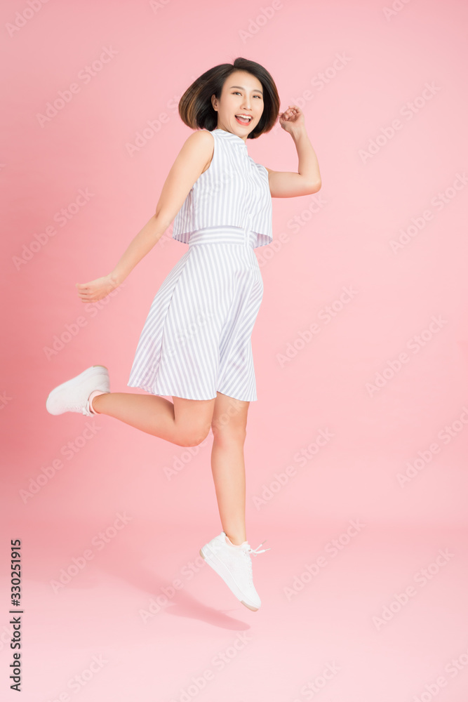 Freedom in moving. Surprised, pretty, happy young woman jumping and gesturing against pink studio background