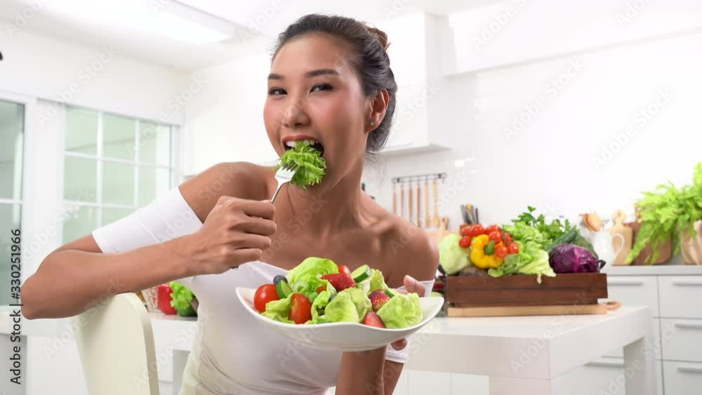 Beautiful Young woman eating salad in the kitchen . Beautiful Young woman eating salad in the kitchen .