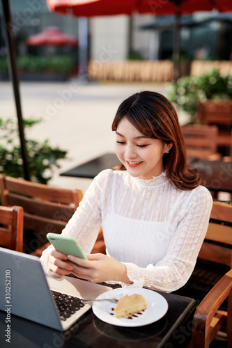 Smiling beautiful young woman talking on smart phone in the city