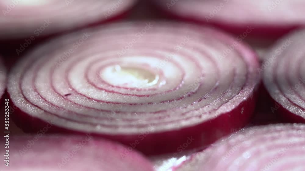 Sliced red onion rings rotating on white in 4K. Closeup top view of healthy food background with vegetable of rich vitamin.
