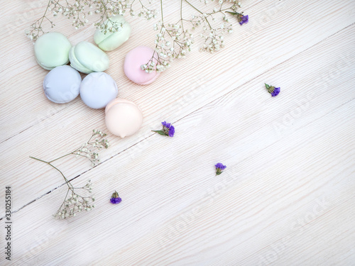 French round sweetness of the marshmallows and the delicate airy flowers on white wooden table