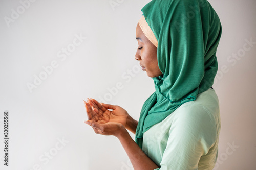 Close up picture of a young muslim woman praying. Young Muslim woman Praying with folded hands. She has a green veil covering her head. Young muslim woman praying in mosque photo