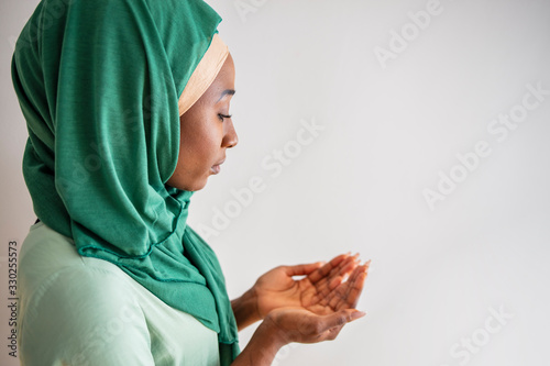 Close up picture of a young muslim woman praying. Young Muslim woman Praying with folded hands. She has a green veil covering her head. Young muslim woman praying in mosque photo