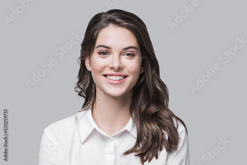 Beautiful young business woman portrait, Smiling cute girl with long hair studio shot, Isolated on gray background	 photo